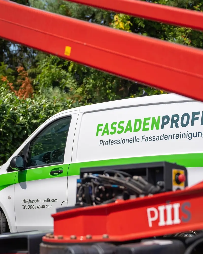 Firmenwagen von FassadenProfis neben dem roten Hubsteiger
